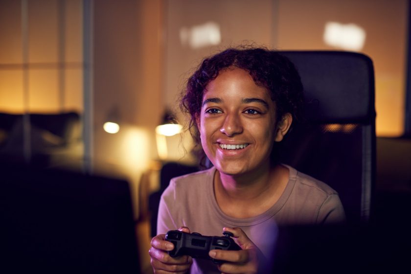 Teenage Girl With Game Pad Sitting In Chair and Gaming At Home